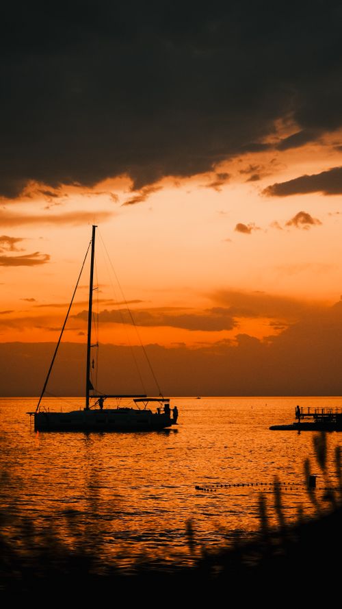 Free Silhouette of a sailboat at sunset creates a tranquil seascape scene. Stock Photo