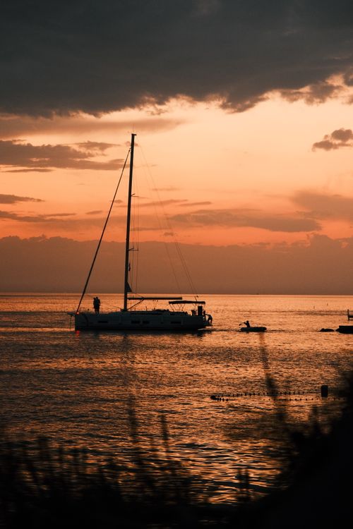 Free A sailboat glides on the water at sunset, capturing serene oceanic tranquility. Stock Photo
