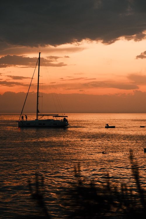 Free Sailboat drifting on calm waters during a vibrant sunset, creating a tranquil and picturesque scene. Stock Photo