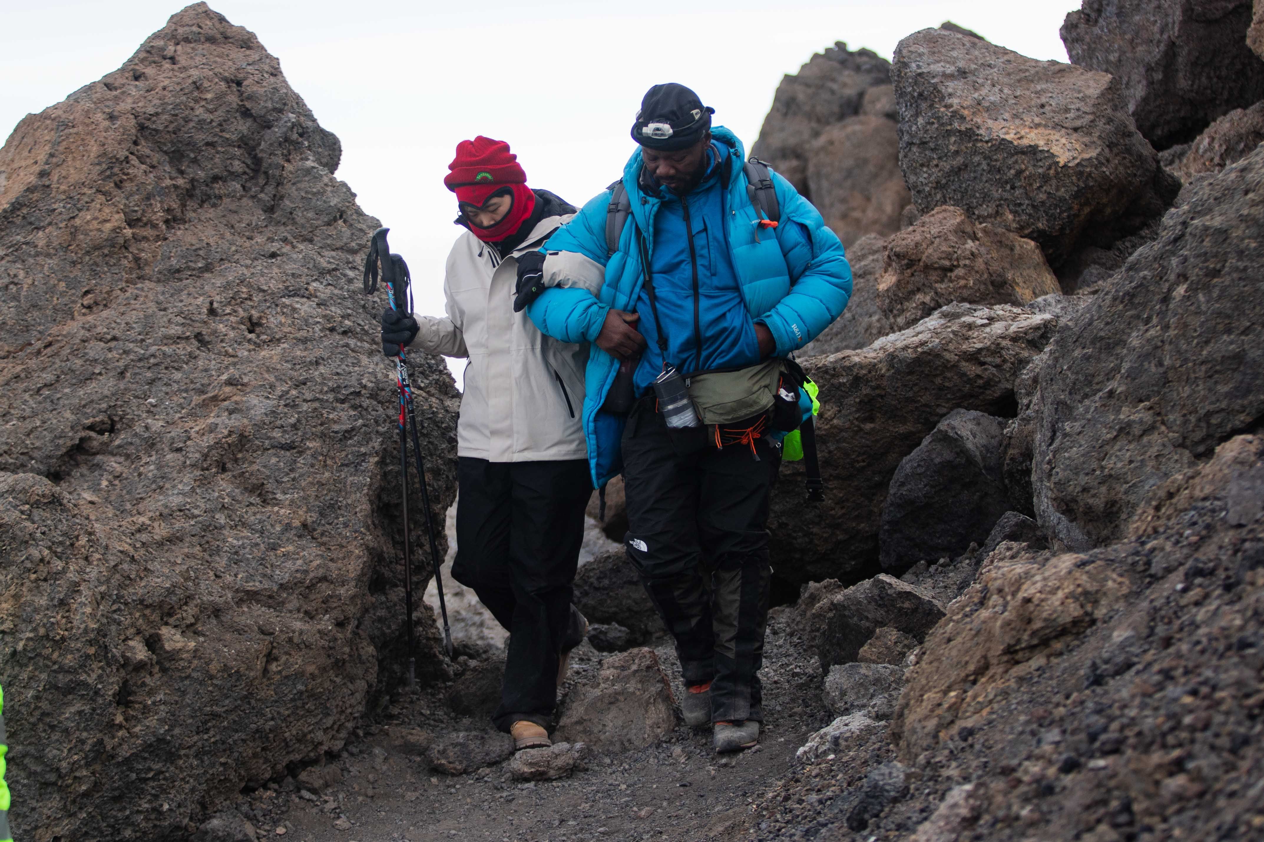 Outstanding 9 Days - Best of Tanzania Safari Review: The Ultimate Northern Circuit Adventure Review 2026 - Two climbers carefully navigate down a rocky mountain trail in cold weather gear.