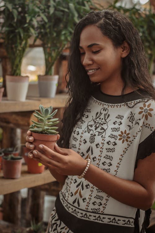 Woman In White And Black Shirt Holding A Plant