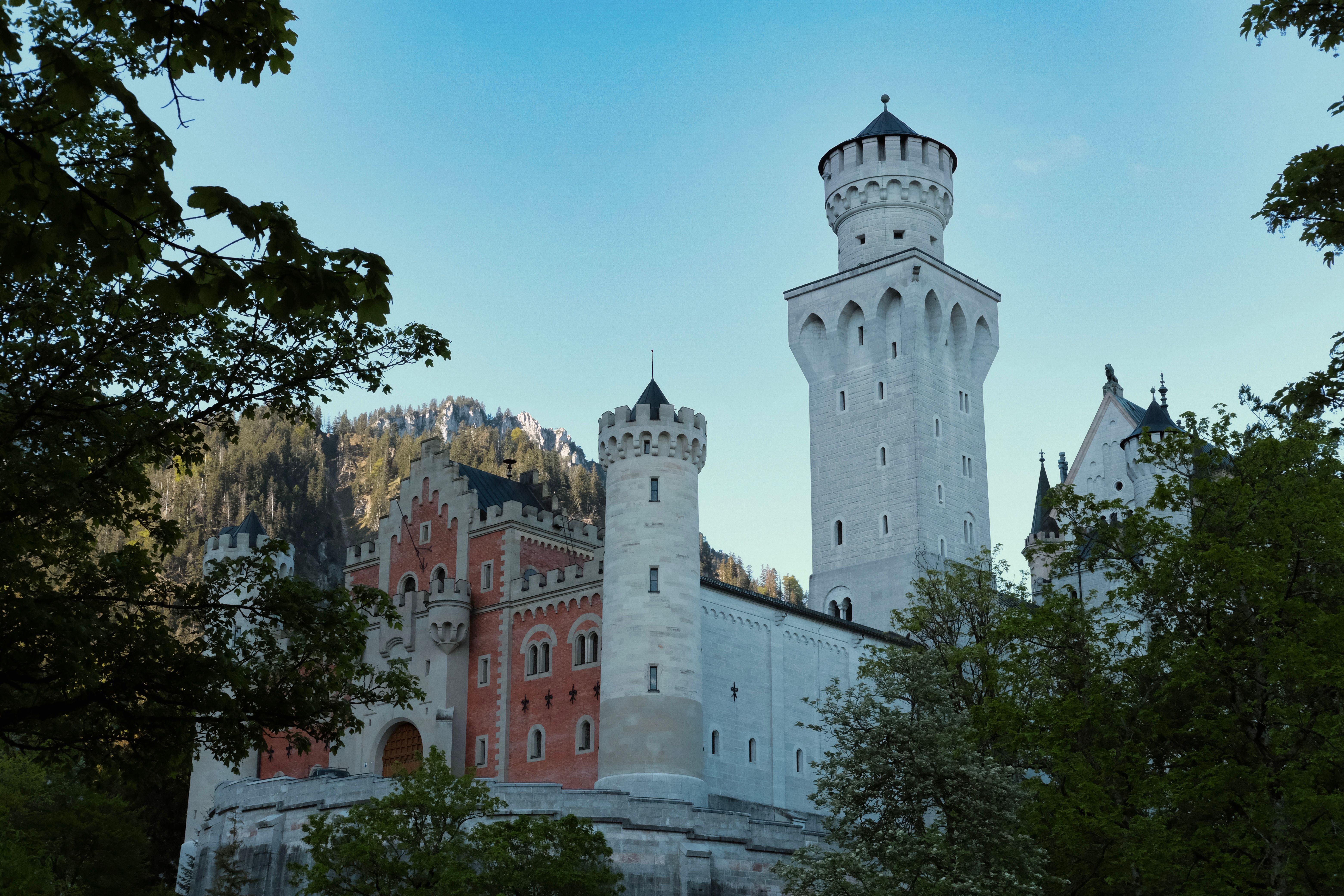 Scenic view of Neuschwanstein Castle's towers surrounded by lush greenery in Schwangau, Germany.