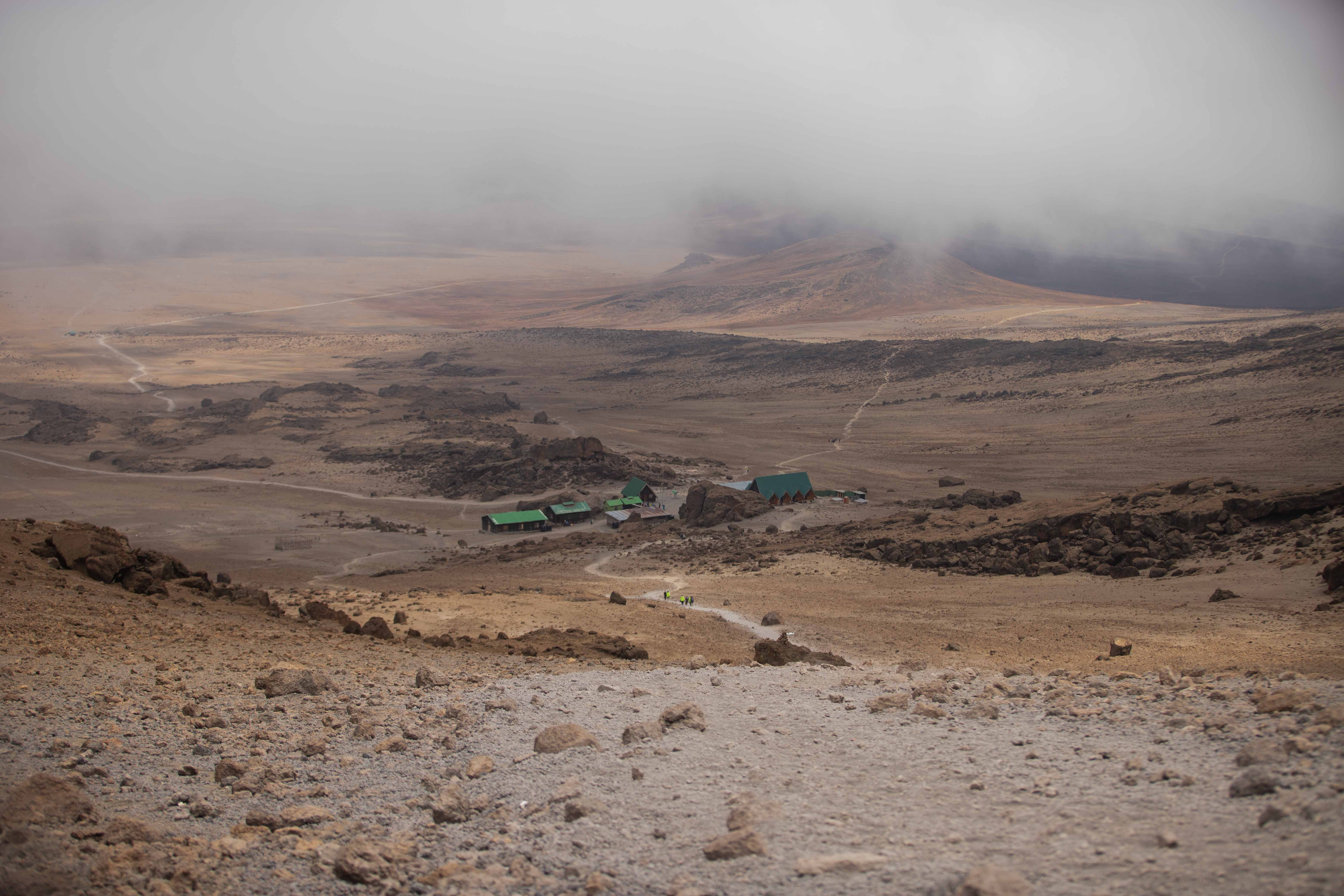 Incredible 7 Days Mount Kilimanjaro Climbing via Machame Route Review 2026 - A misty and barren landscape in Mount Kilimanjaro National Park with huts visible.