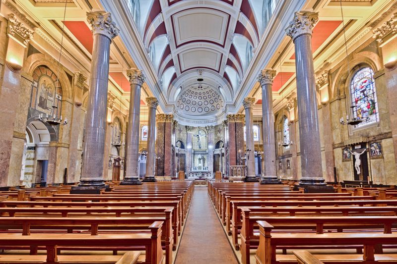 Bright view of a historic church interior in Preston, England, showcasing grand pillars and stained glass windows.
