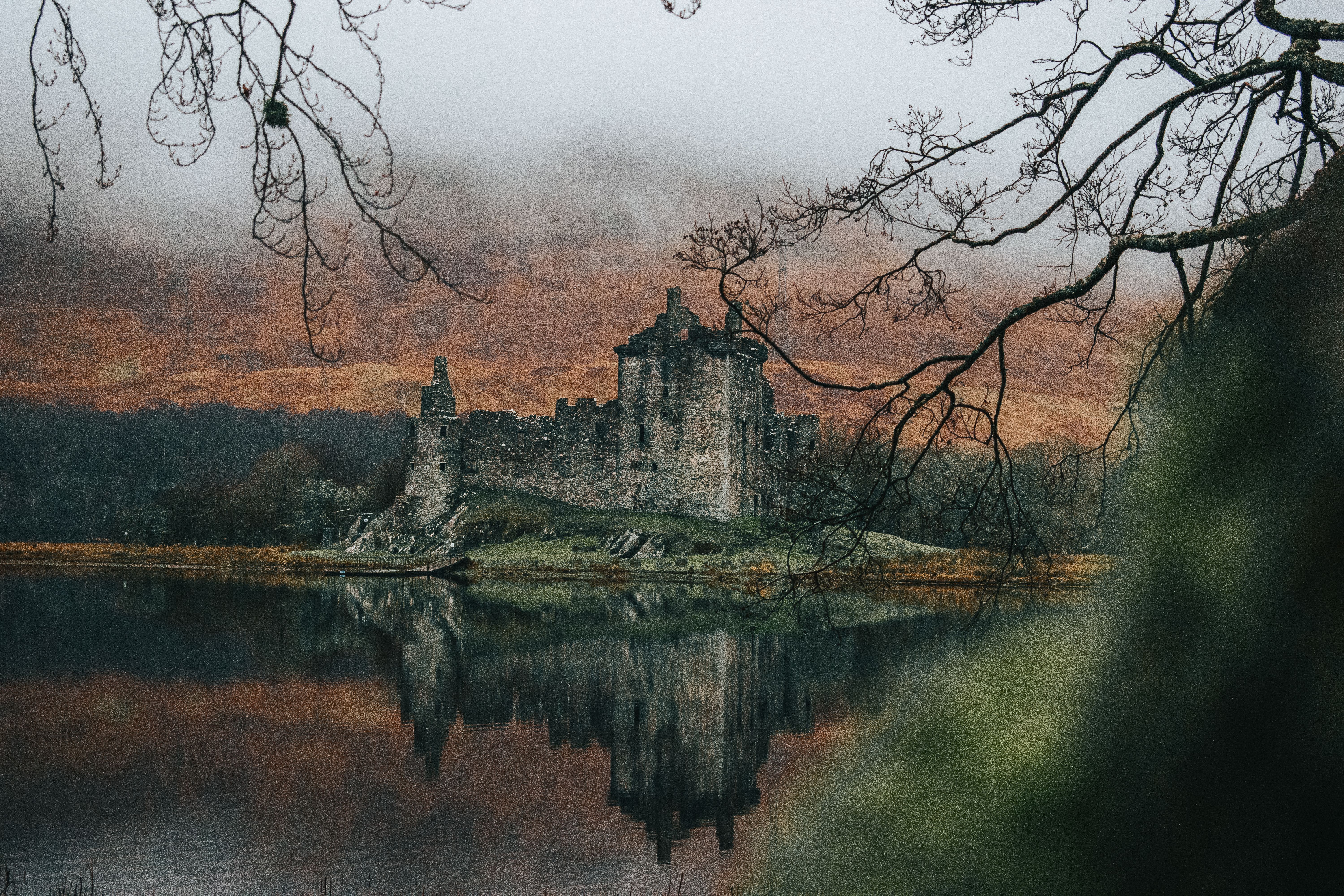 A misty view of Kilchurn Castle reflecting on Loch Awe during autumn.