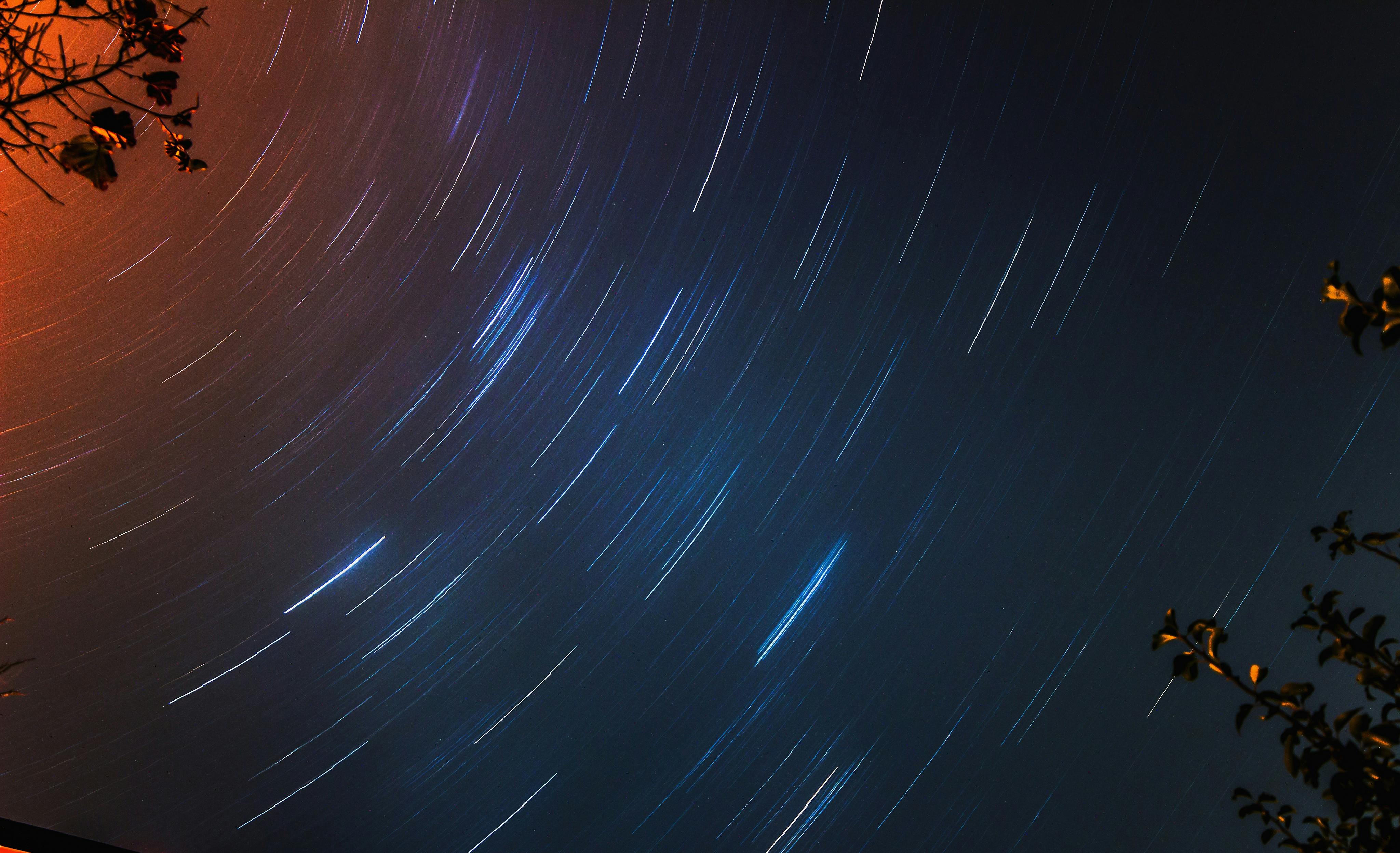 在晴朗的夜空中，利用树枝捕捉星轨，创造出圆形图案