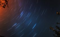 在晴朗的夜空中，利用树枝捕捉星轨，创造出圆形图案