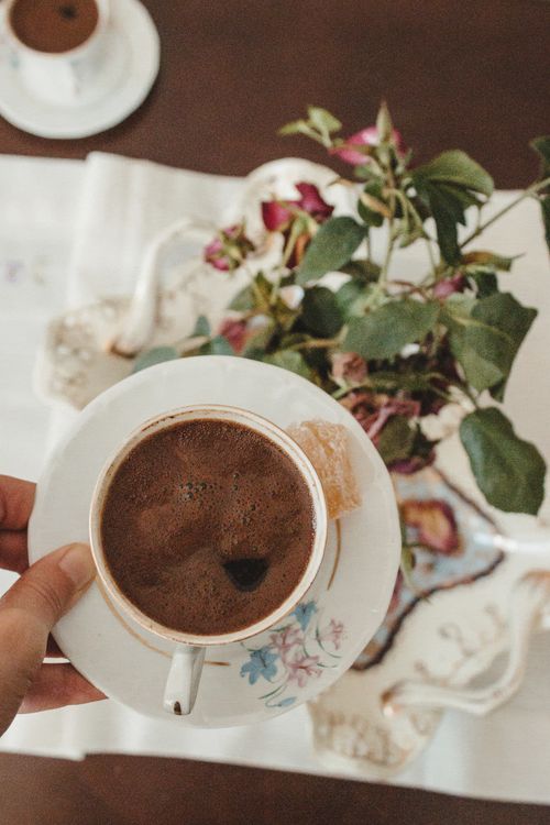 Free Top view of a hand holding a coffee cup with floral decorations and a plant centerpiece. Stock Photo