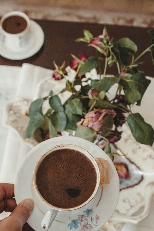 Free Aesthetic coffee setup with cup and saucer, floral arrangement in vintage style. Stock Photo