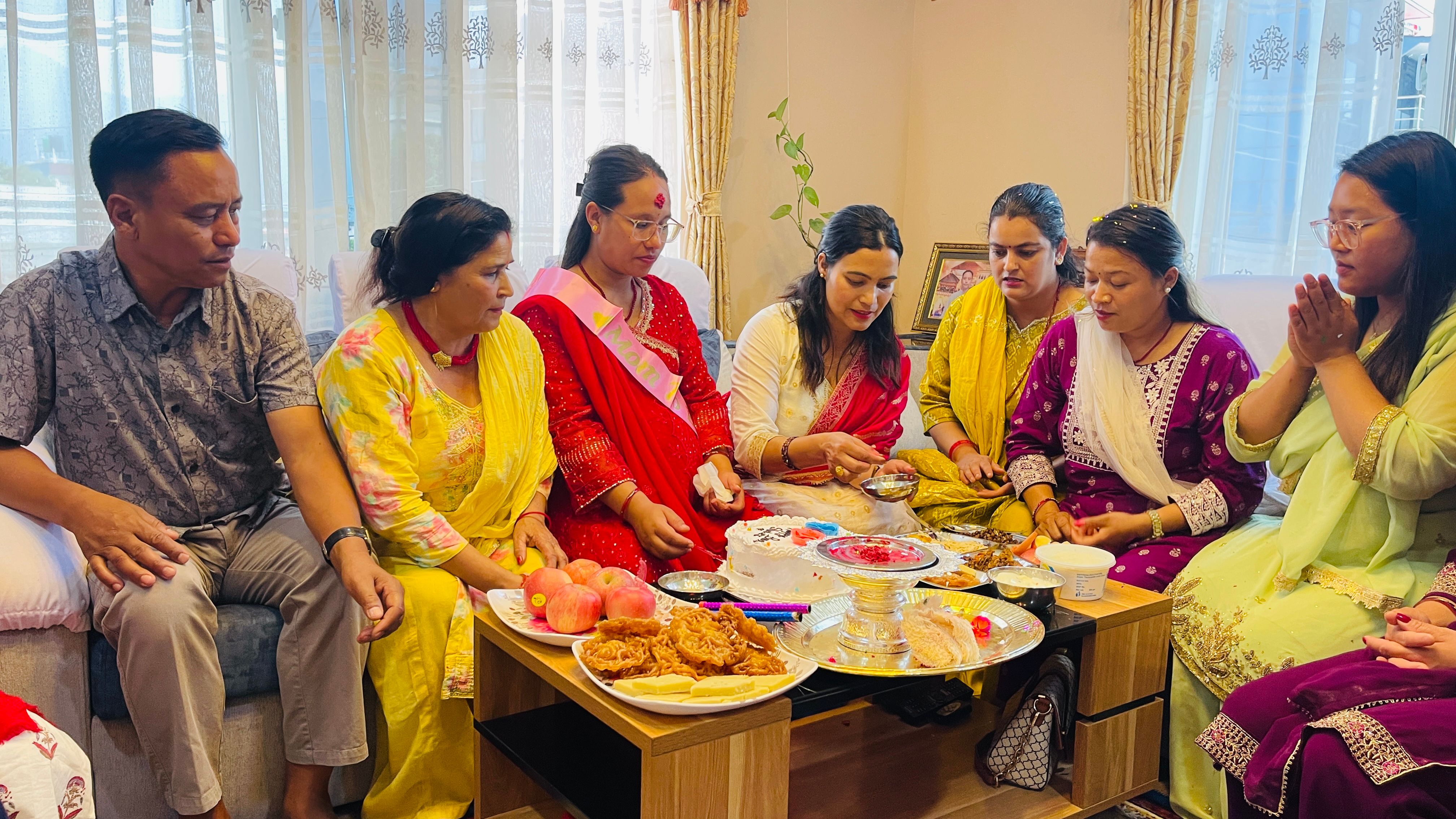 A family gathers indoors for a traditional Nepali celebration with food and ritual offerings.