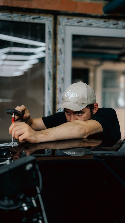 Free A dedicated technician repairing a car indoors, showcasing precision and skill. Stock Photo