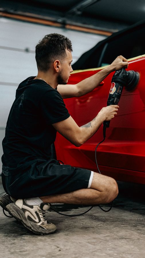 Detailer polishing a red car