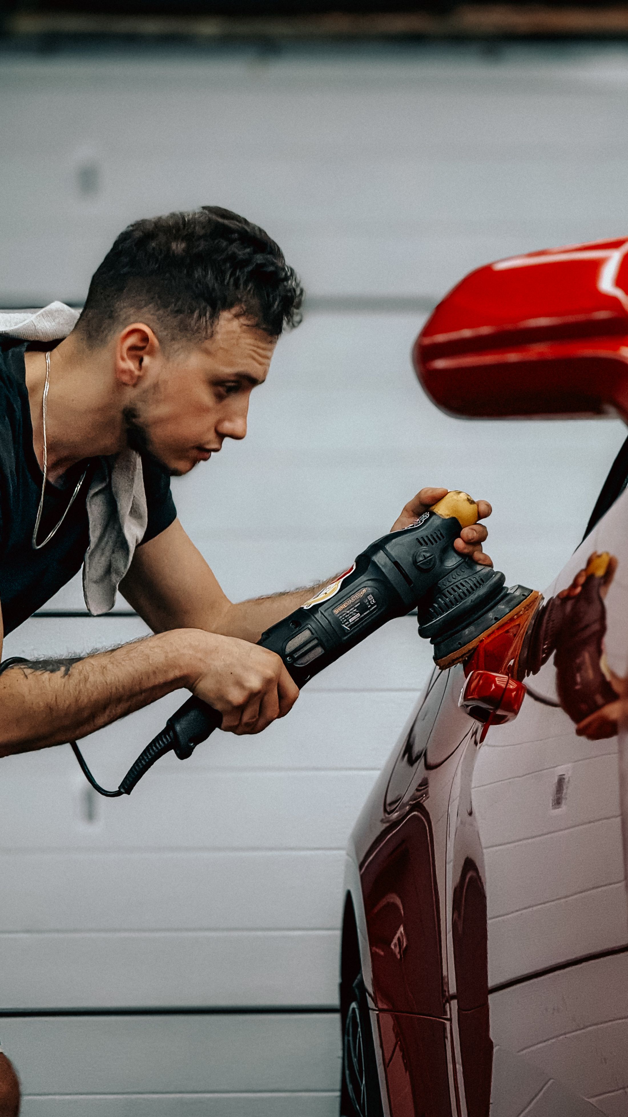 Detailer polishing a red car with a buffer