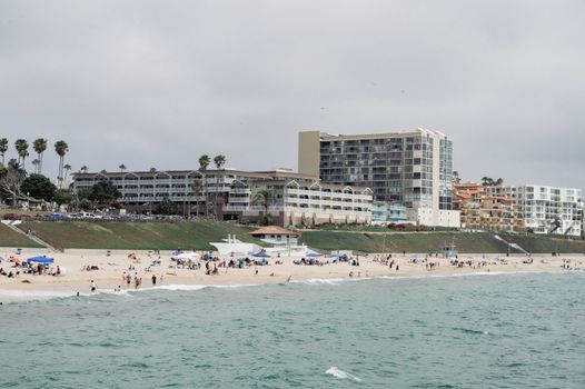 Vibrant day at a busy Californian beach with modern beachfront hotels.
