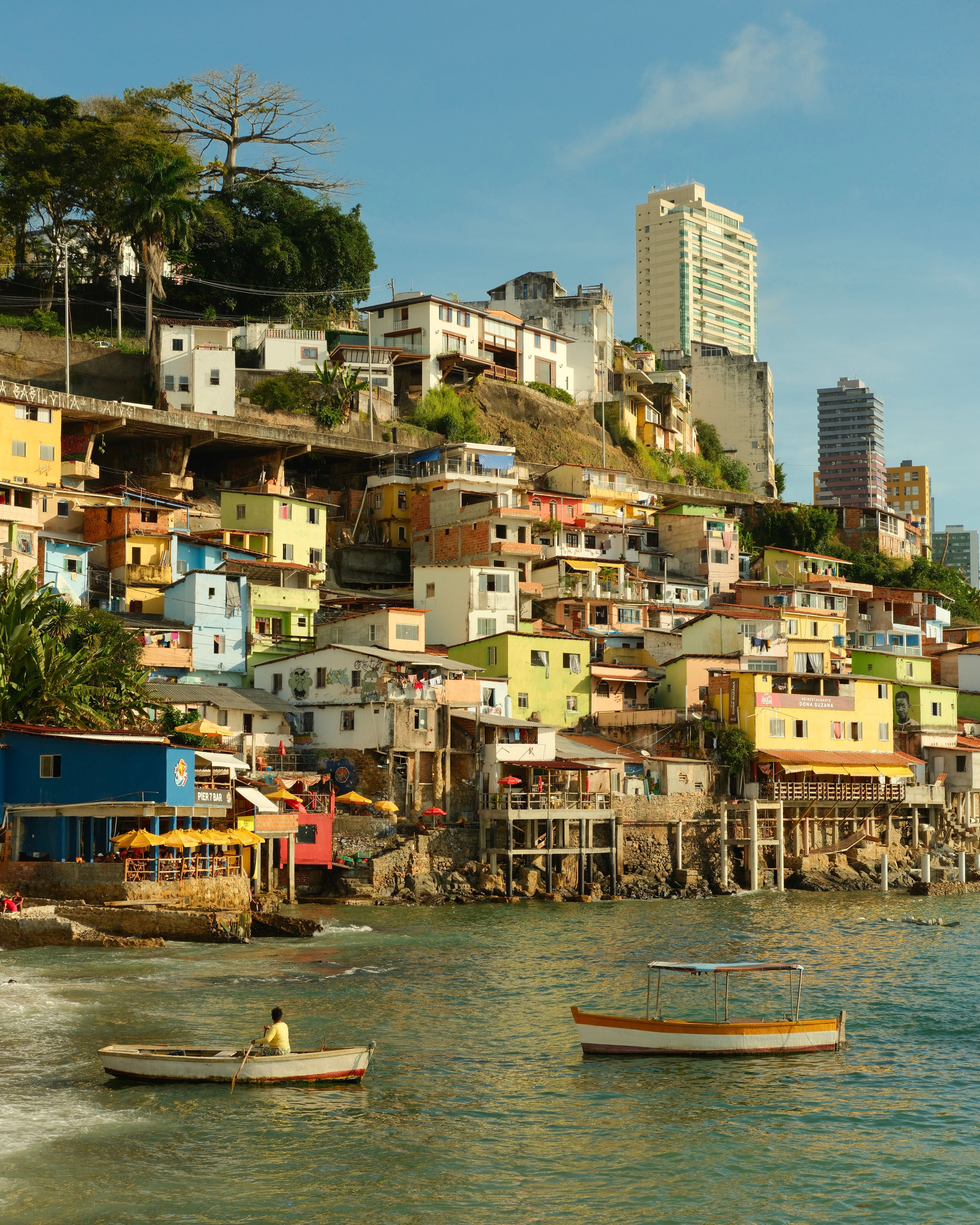 Vibrant hillside favela by the sea with boats in Salvador, Brazil.