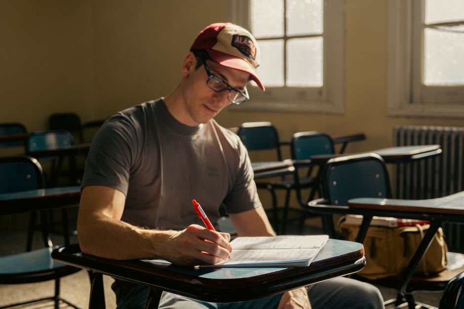 Adult male student studying at a university classroom desk during the day. Adult male student studying at a university classroom desk during the day.