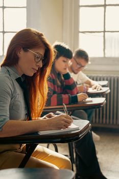 Students attentively writing notes during a classroom lecture in a university setting.
