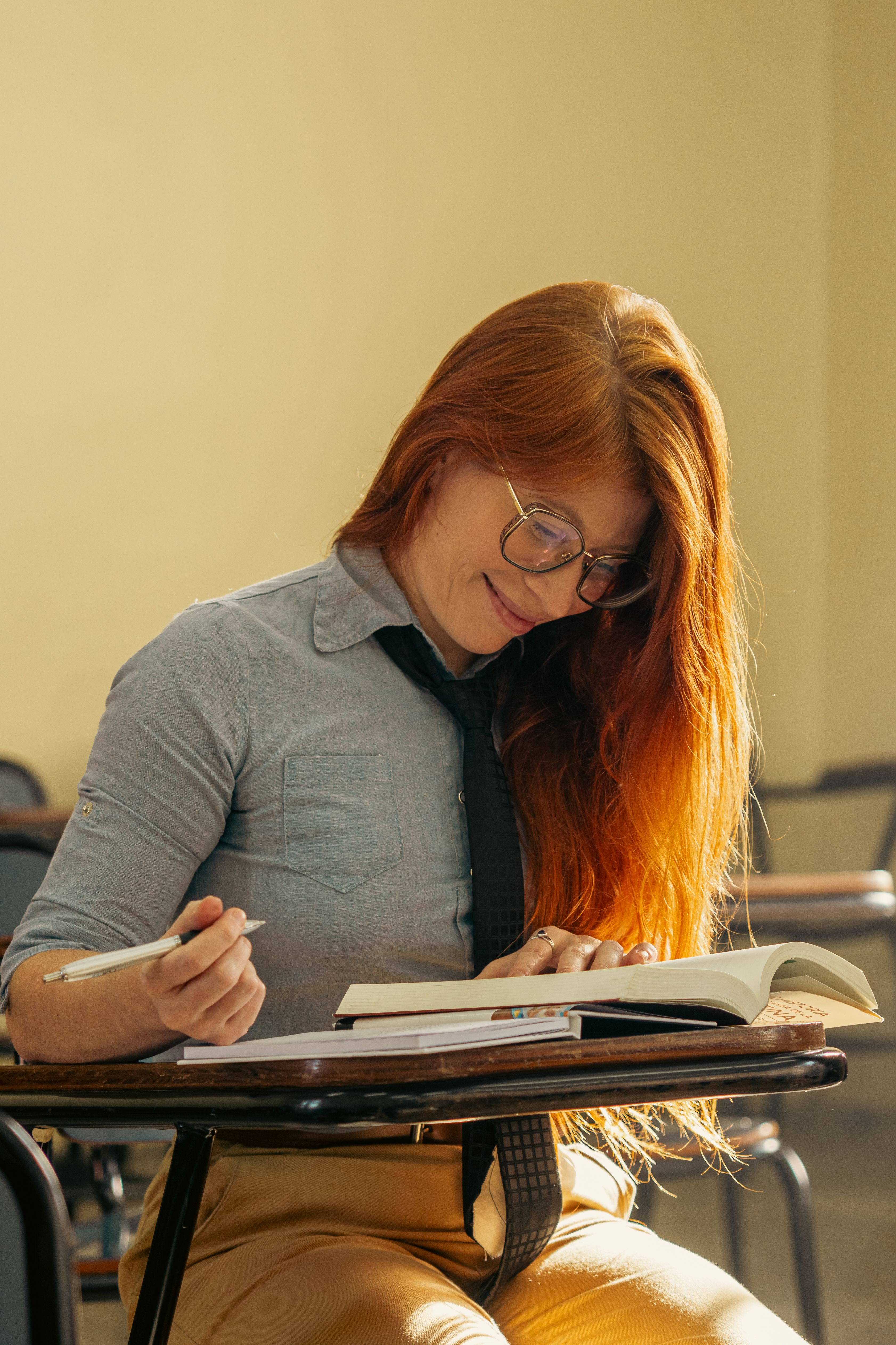 Young woman with red hair focusing on her studies in a university classroom.