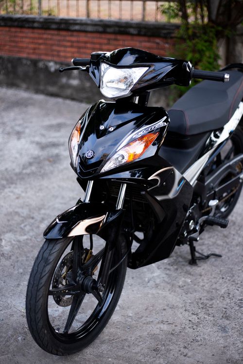 Free Close-up of a black motorcycle parked outdoors on a concrete surface. Stock Photo