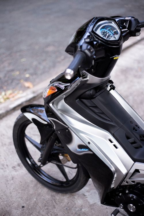 Free Close-up of a stylish black and silver motorbike parked outdoors on a sunny day. Stock Photo