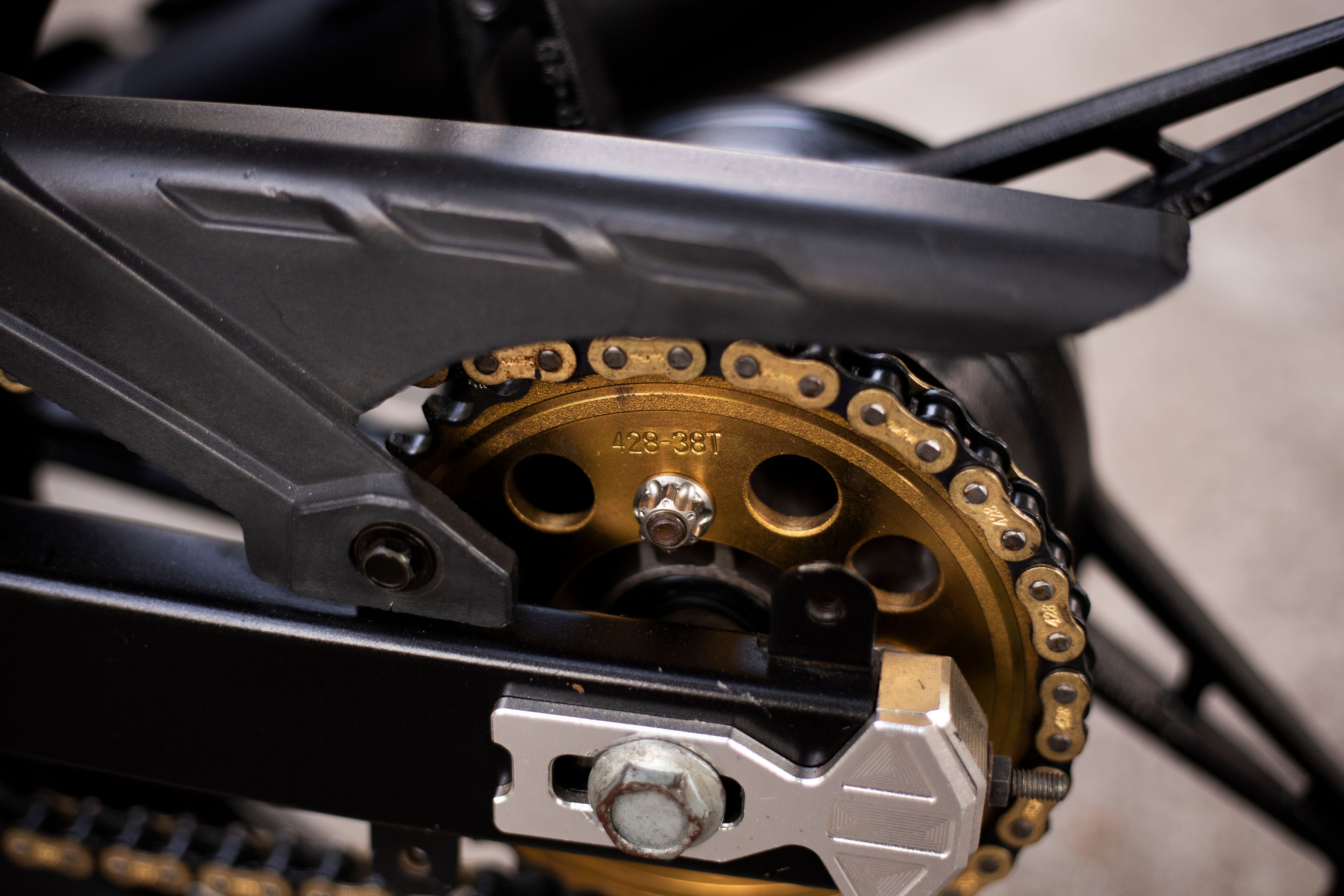 Detalhe da corrente, coroa e pinhão de uma moto usada durante inspeção