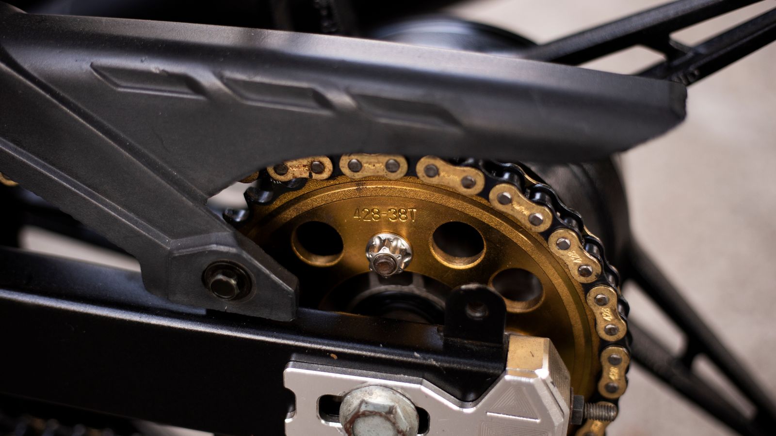 Detalhe da corrente, coroa e pinhão de uma moto usada durante inspeção