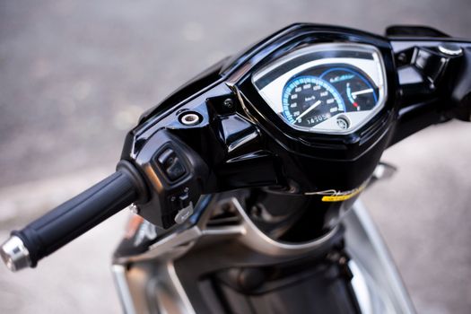 Detailed view of a black motorcycle handlebar and speedometer, showcasing design and functionality.