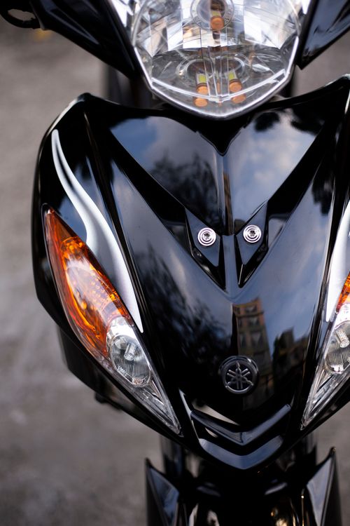 Free Close-up of a black motorcycle's front with reflections on a shiny surface. Stock Photo