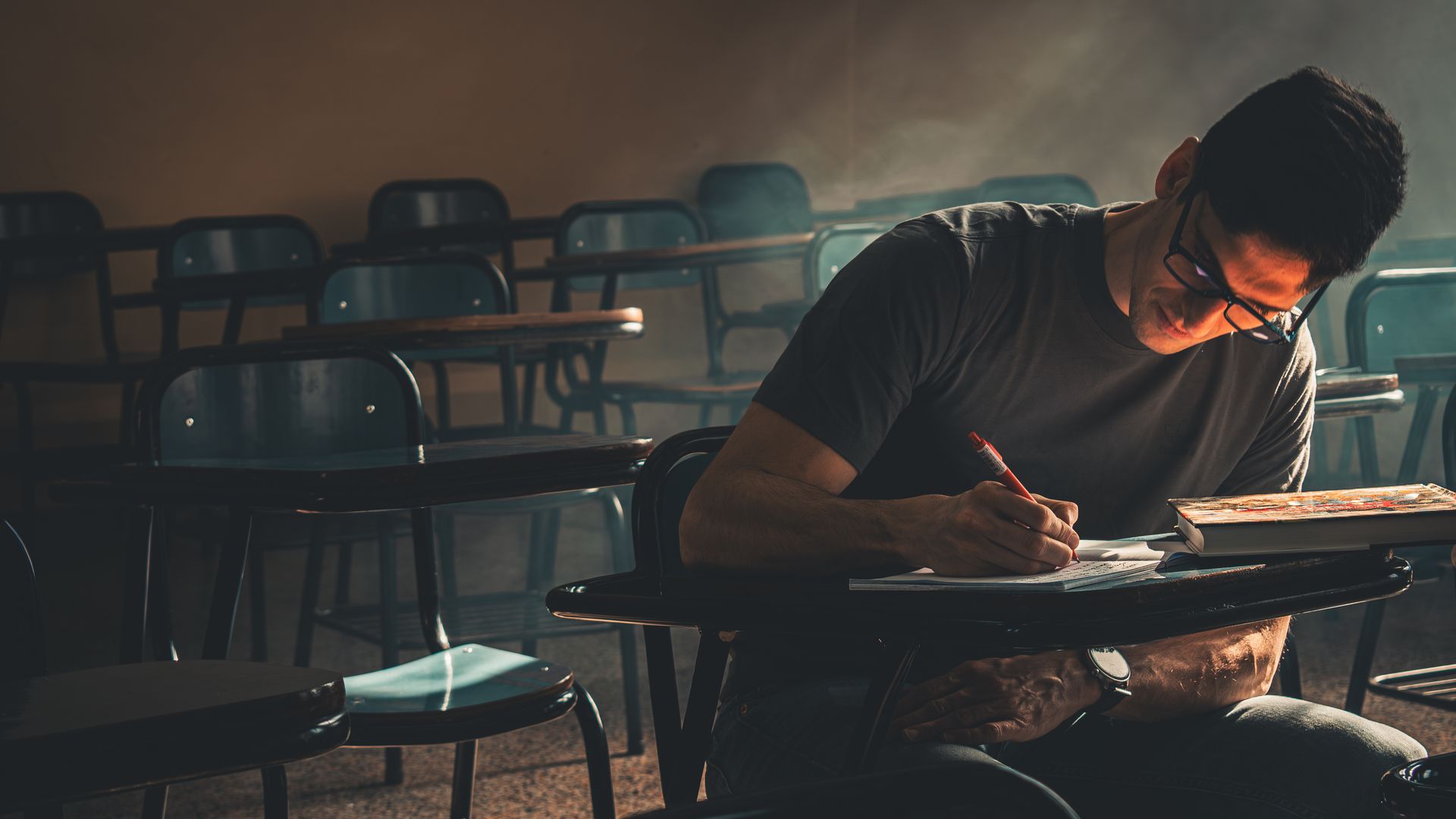 Modafinil Concentration: Boost Your Focus and Productivity Student focused on writing, studying in a dimly lit empty classroom — modafinil concentration