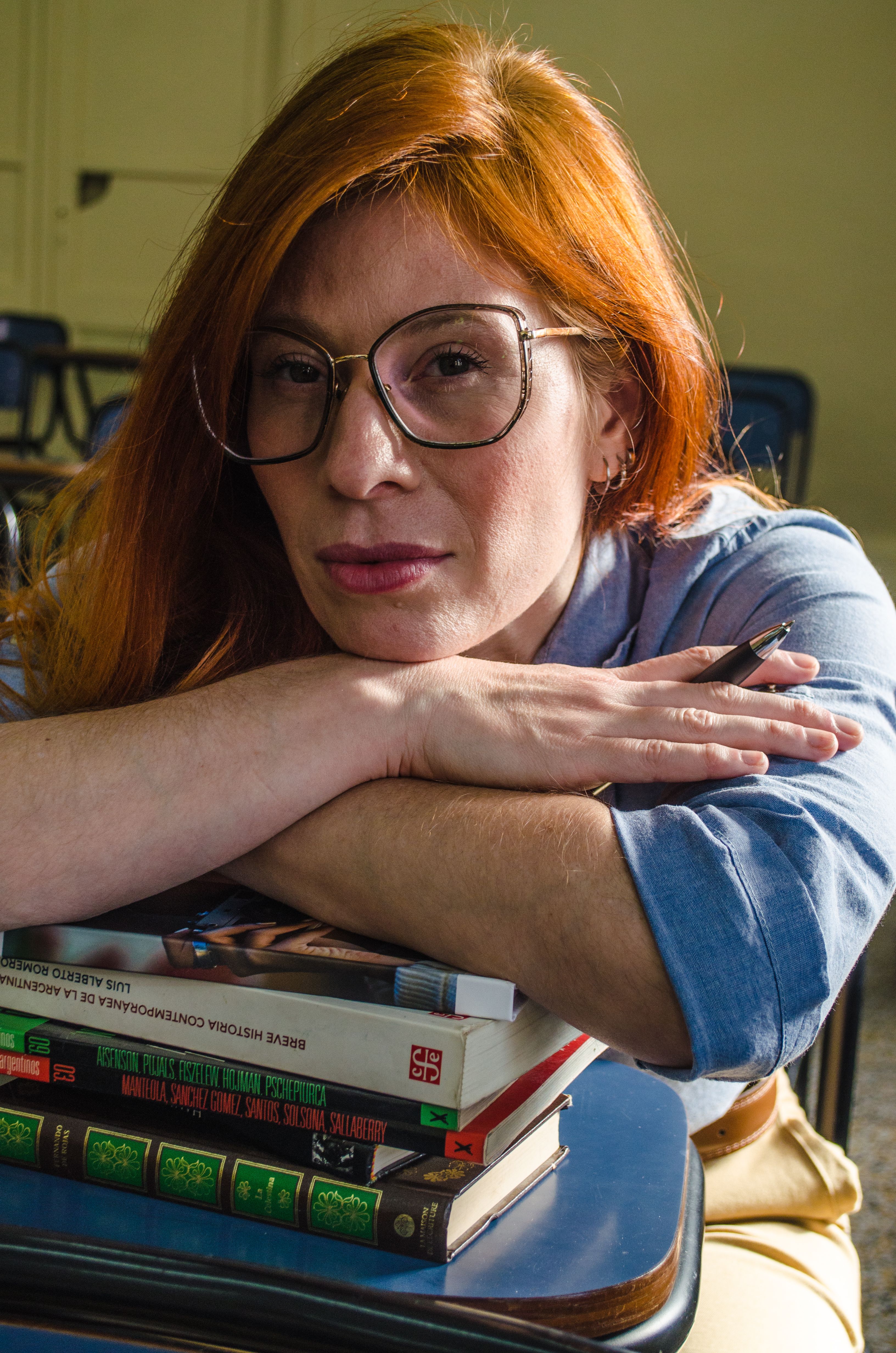 Portrait of a young woman in a Buenos Aires classroom, resting on books.