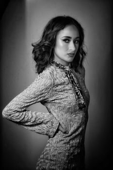 Black and white portrait of a stylish woman posing indoors.