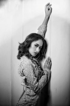 Black and white portrait of a model posing gracefully against a wall.