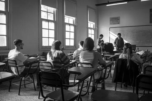 Free A black and white image of students in a classroom engaging in discussion with a teacher. Stock Photo