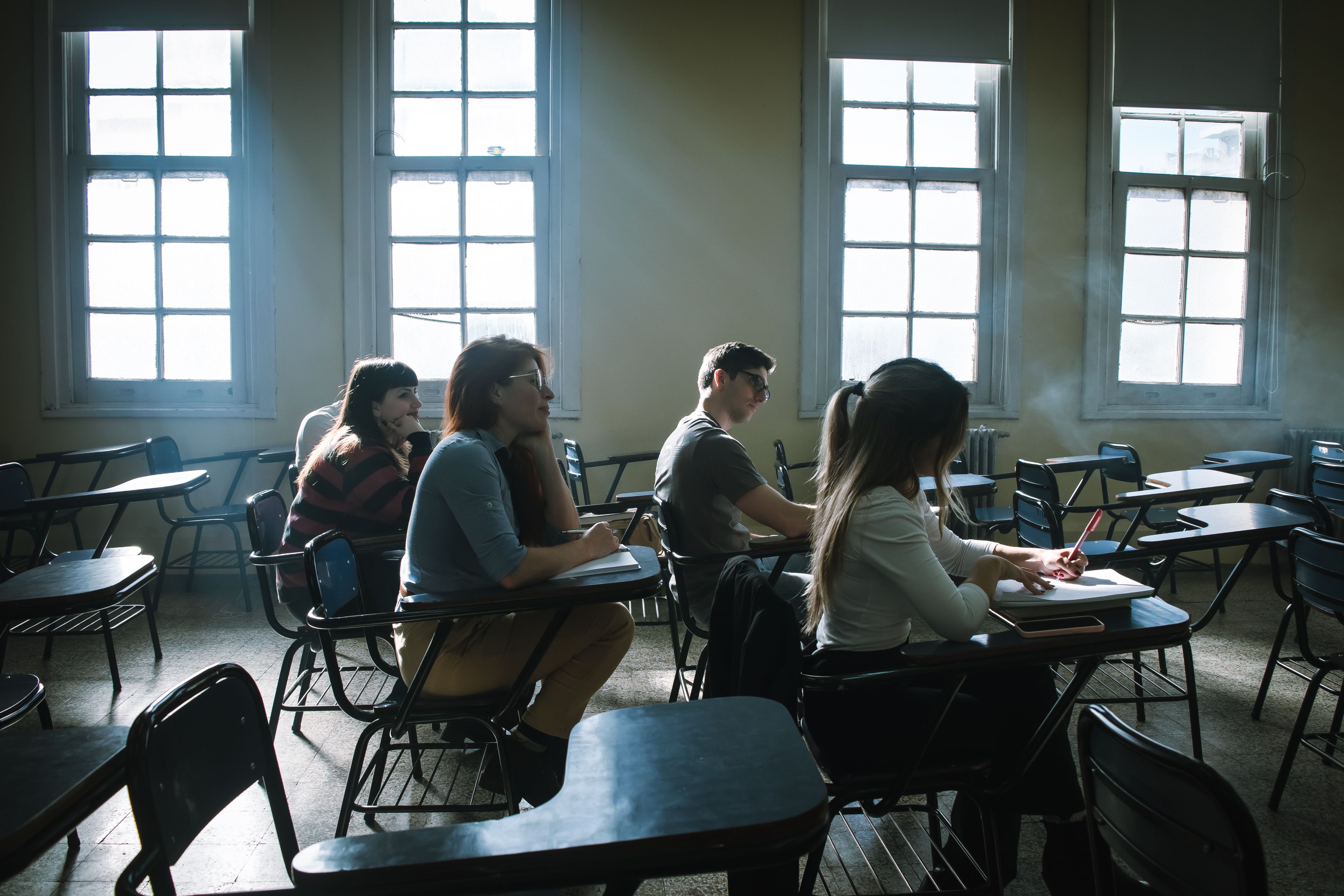 abandoned school classroom with desks and sunlight streaming through windows