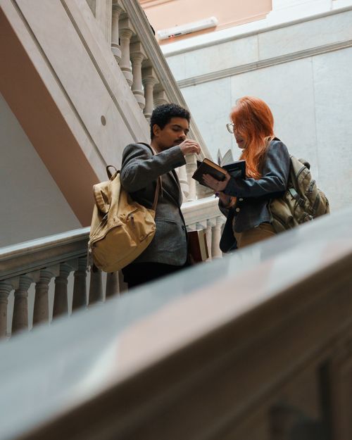 Free Two students with backpacks discuss notes on a staircase in Buenos Aires, Argentina. Stock Photo