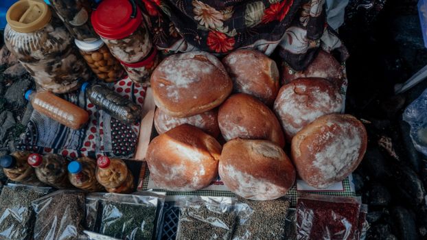 An assortment of fresh breads and preserved goods on a market stall, showcasing diverse culinary offerings.