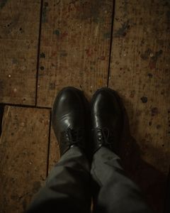 Black leather shoes standing on a rustic wooden floor, offering a vintage feel.