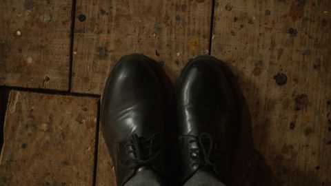 Black leather shoes standing on a rustic wooden floor, offering a vintage feel.