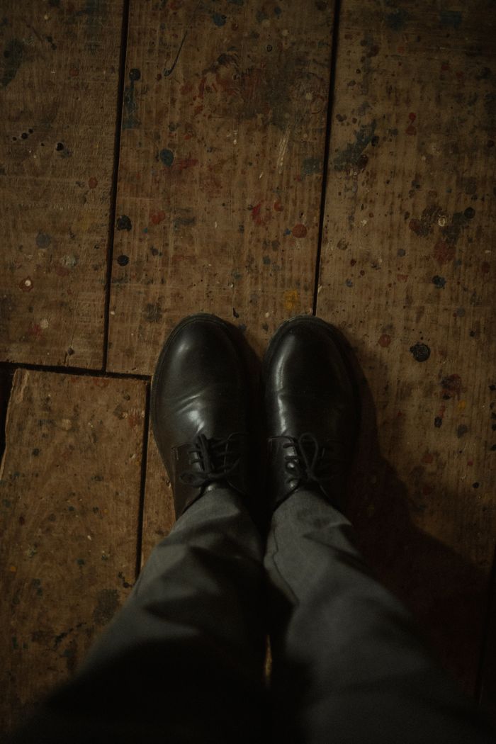 Black leather shoes standing on a rustic wooden floor — photo by Alexander Mass on Pexels