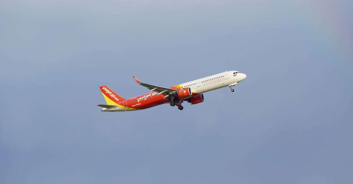 An airplane from the airline VietJet in mid-flight against a clear blue sky.