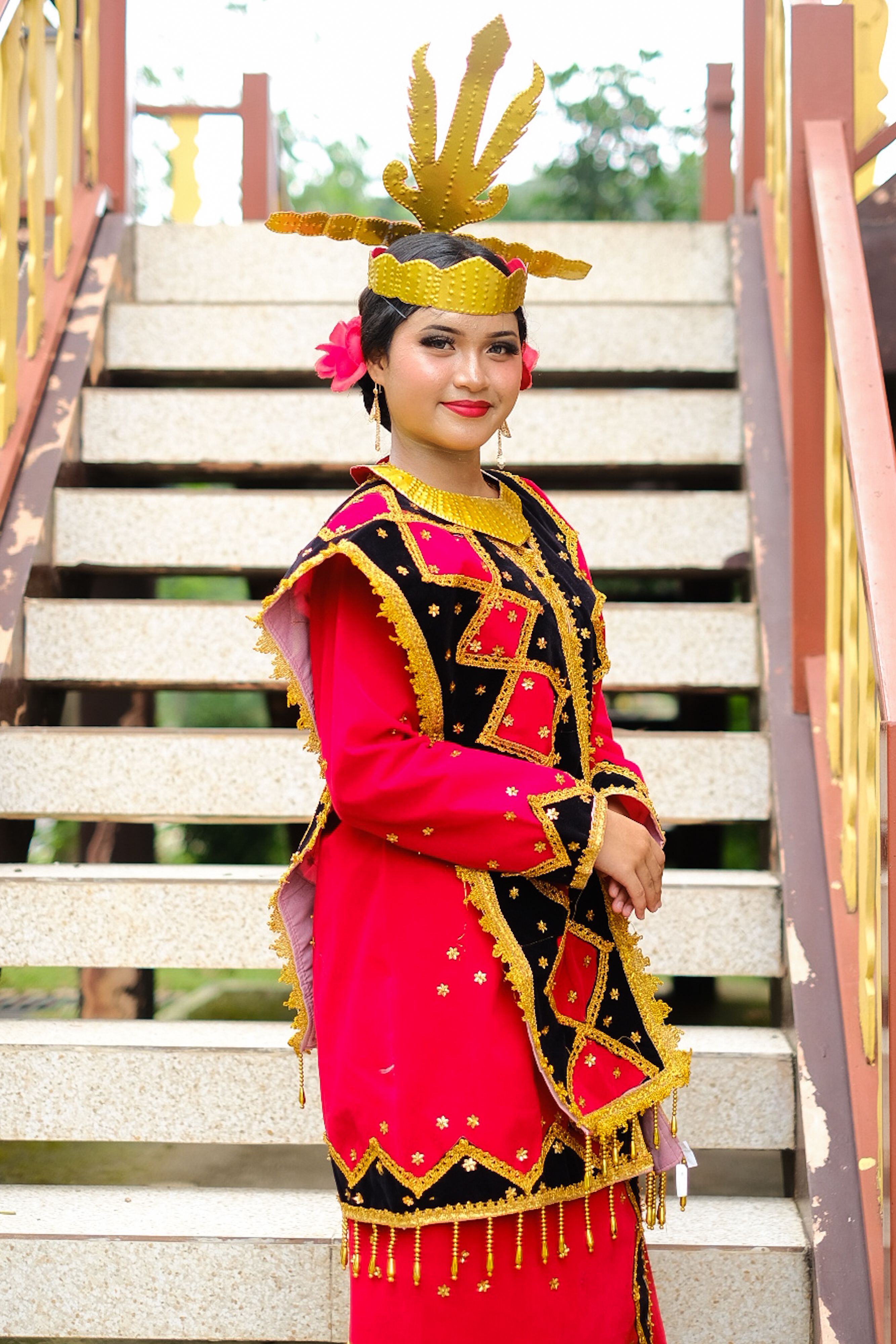 Portrait of a woman in traditional Indonesian dance attire on stairs.