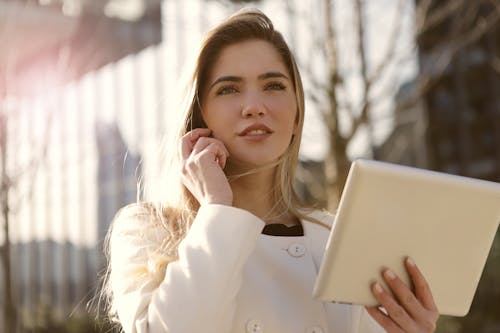 Woman in White Long Sleeve Shirt Holding A Tablet