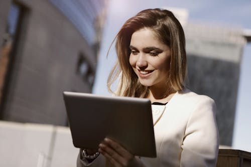Woman in White Blazer Holding A Black Tablet