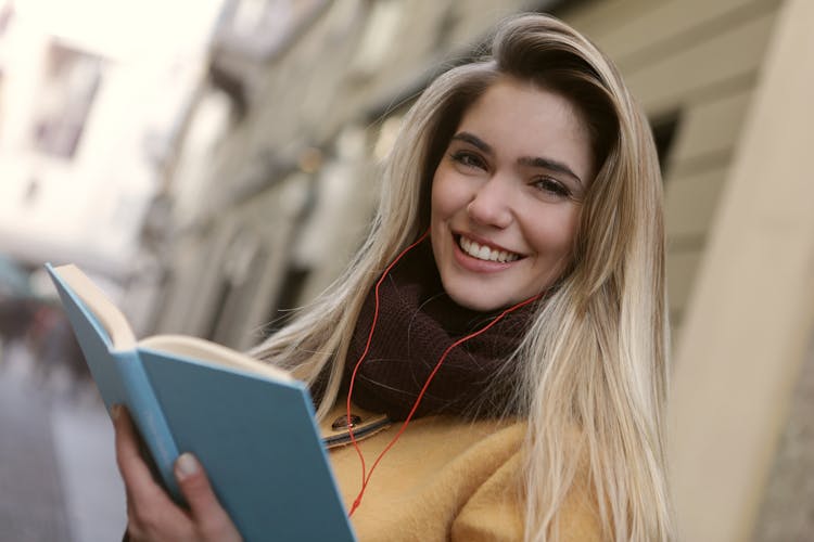 Woman In Brown Coat Holding A Blue Book