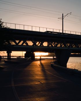 Silhouette of a bridge over Tempe Town Lake during sunset with people walking.