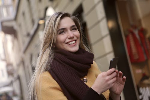 Woman In Brown Scarf Holding A Smartphone