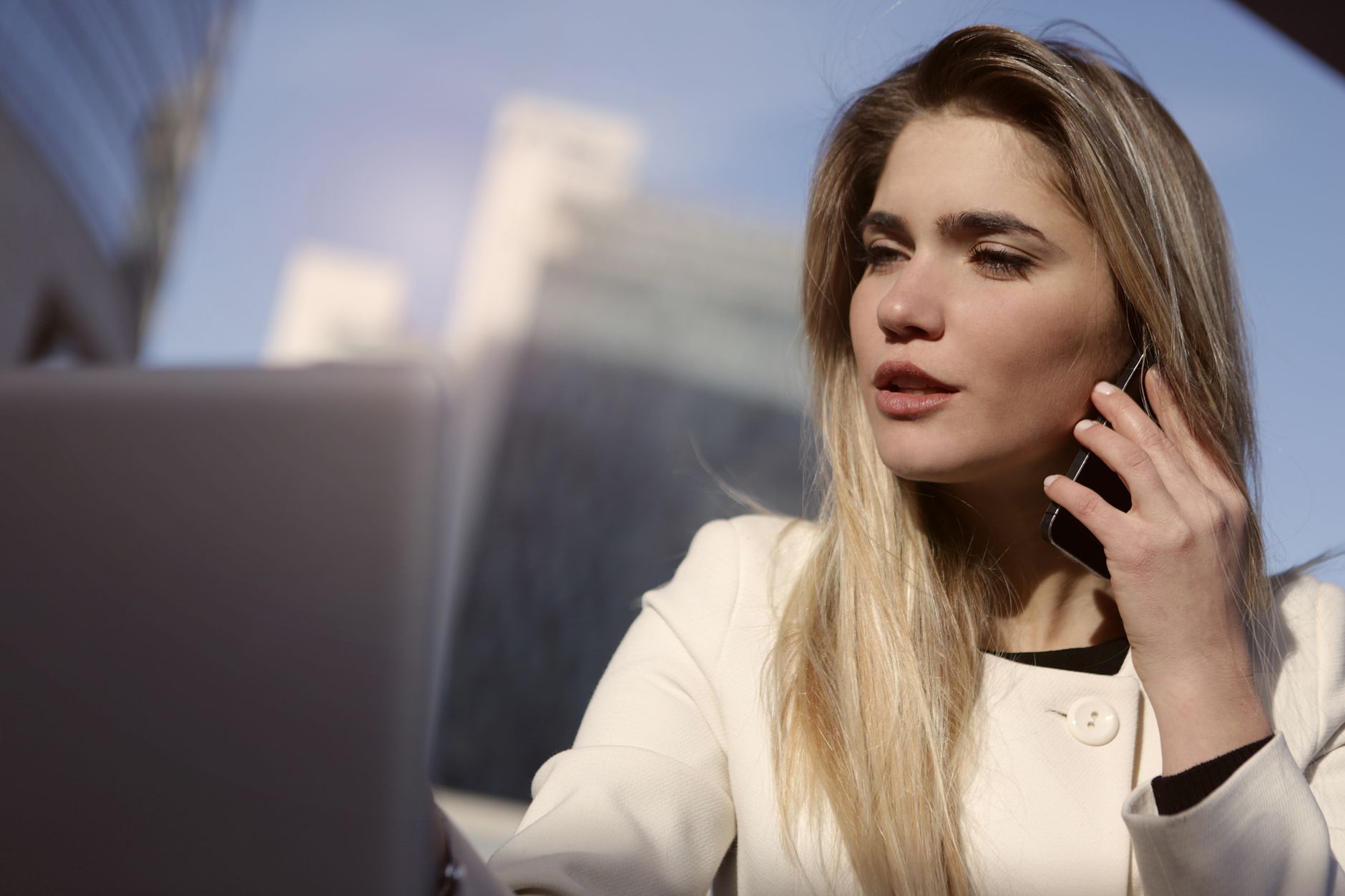 Offer Social Media Services Using Your Phone (Quick Start) A blonde businesswoman on a smartphone outside a modern building