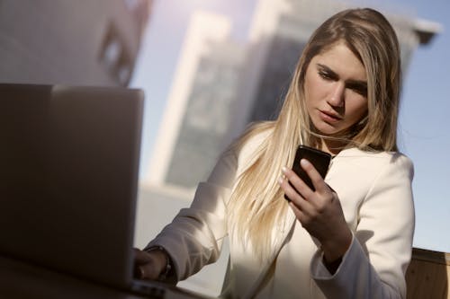 бесплатная Женщина в белом пиджаке с черным смартфоном Стоковое фото