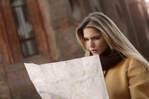 Женщина в коричневой рубашке с длинным рукавом держит карту