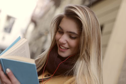 Kitap Okurken Gülümseyen Kadının Sığ Odak Fotoğrafı